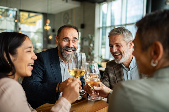 Happy colleagues toasting white wine at restaurant
