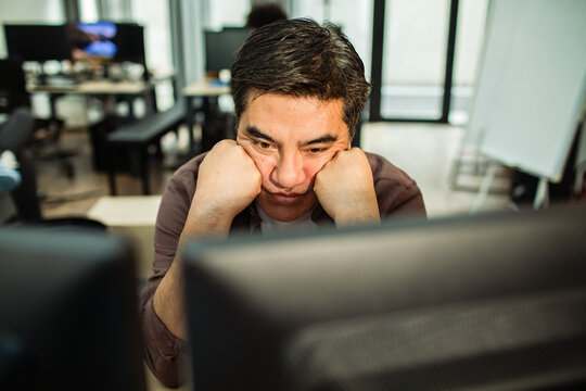 Frustrated man staring at computer in modern office