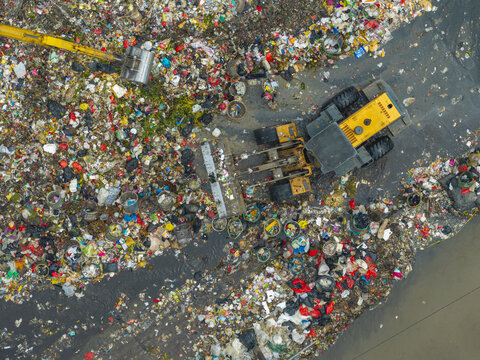 Aerial view of a landfill site with heavy machinery moving piles of waste and garbage in Jakarta, Indonesia.
