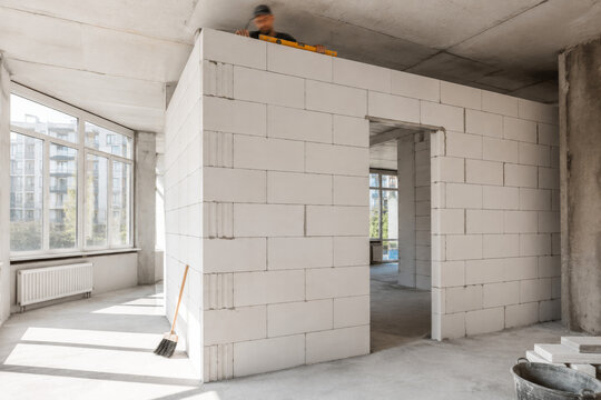 Trabajo en construcci&oacute;n de una pared en un espacio interior con ventanas grandes que dan luz natural al &aacute;rea