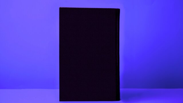Blank hardcover journal book standing upright on flat purple stage surface