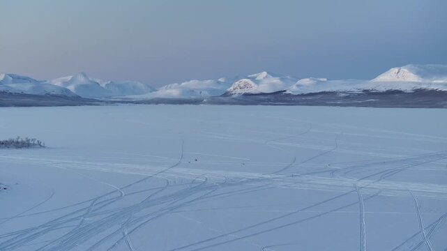 Rentierfamilie auf einem gefrorenen See in Lappland, Finnland. Schneelandschaft in einer Polarnacht bei klarem Himmel. Dicke Eisschicht auf dem See. Drohne Mavic 3 Pro. D-Log