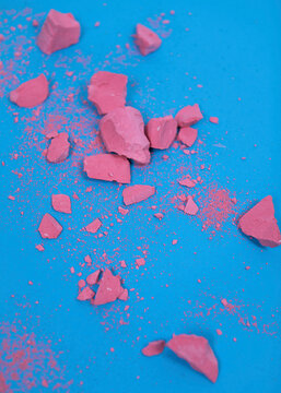 Broken pink chalk scatters across a bright blue background