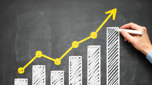 Hand drawing a growing financial business chart with a rising yellow arrow on a dark chalkboard