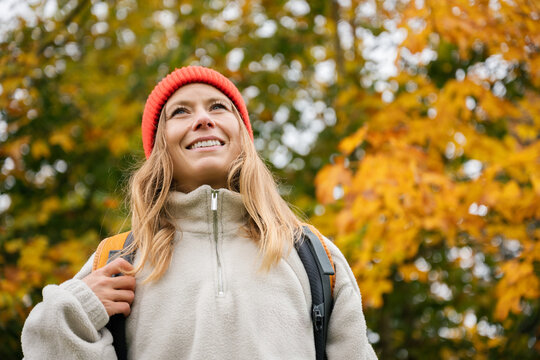 Smiling woman with backpack enjoys outdoor hiking during fall
