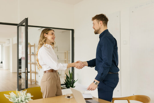 Man and woman shake hands after a successful job interview indoors