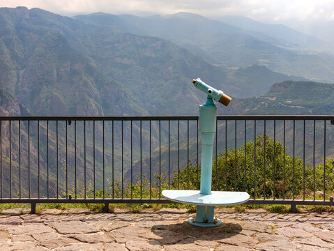 Panoramic mountain vista viewed through public telescope on overlook