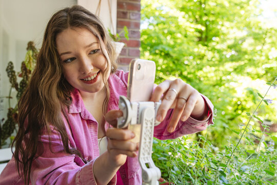 Smiling woman sets up smartphone on tripod for video blog