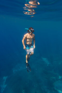 Man with fins and snorkel diving under water