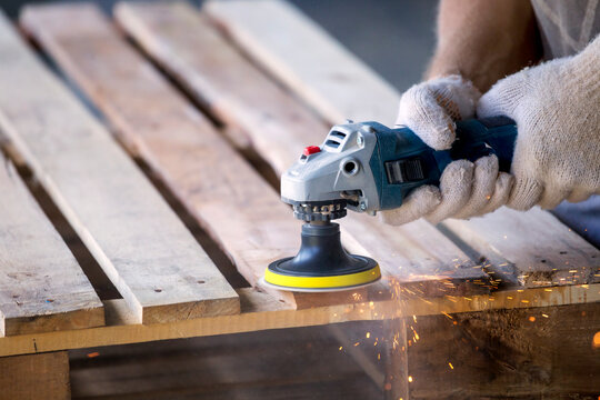 Man sanding pallet with a random orbital sander