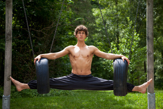 Germany, Bavaria, Young man stretching legs in tyres