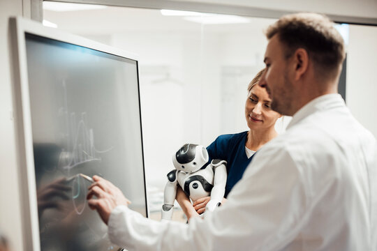 Medical researchers collaborating on AI development with robot and touchscreen