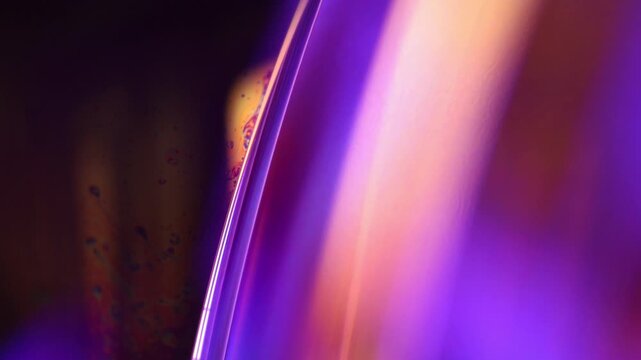Glowing violet fluid boundary with sleek double specular rim and warm bokeh. A sharp, sleek double specular line curves along a vertical liquid film boundary in low-key macro perspective.