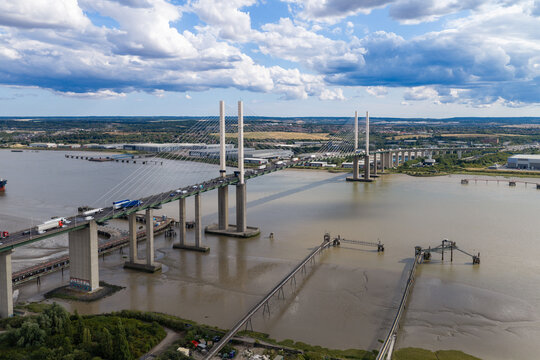 Aerial view of the Queen Elizabeth II Bridge spanning the River Thames with traffic flowing across the cable-stayed structure under a cloudy sky in the United Kingdom.