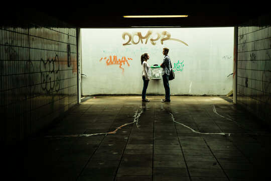 Young couple standing face to face in a dark underpass