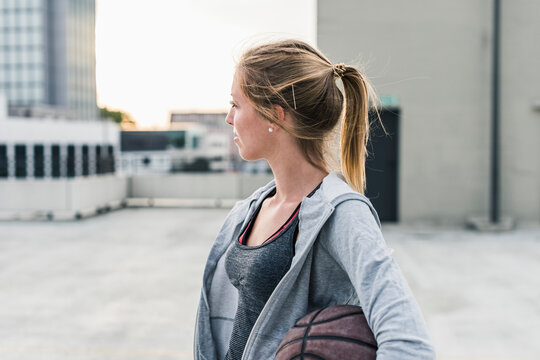 Woman holding basketball on parking level in the city