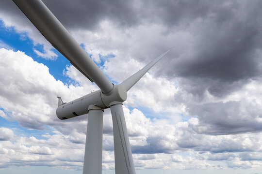 Aerial view of a white wind turbine against a dramatic sky with white and grey clouds in the United Kingdom.
