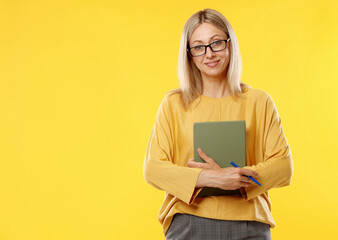 Fototapeta premium Teacher in glasses with notebook and pen on yellow background, space for text