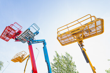 Articulated cherry picker work platforms extended high against sky, representing heavy machinery leasing, asset management, and industry risk © K