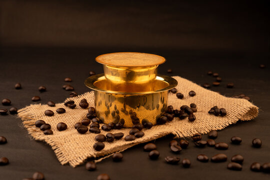 Traditional south indian Brass cup of coffee over beans background
