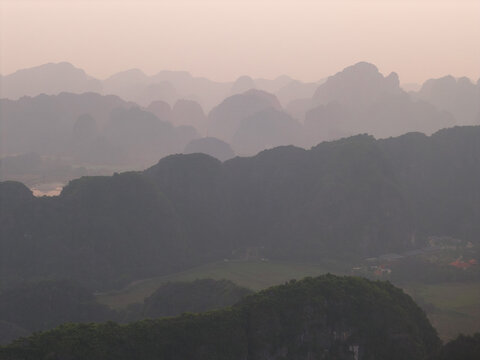 Aerial view of the karst limestone mountains of Tam Coc Bich Dong rising above the lush green landscape in Nam Hoa Lu, Ninh Binh, Vietnam.