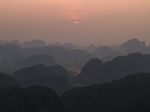 Aerial view of the limestone karst mountains of Tam Coc Bich Dong at sunset with hazy atmosphere in Nam Hoa Lu, Ninh Binh, Vietnam.
