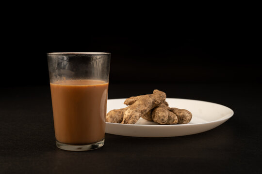 Traditional Indian ginger tea in a clear glass isolated on a black background