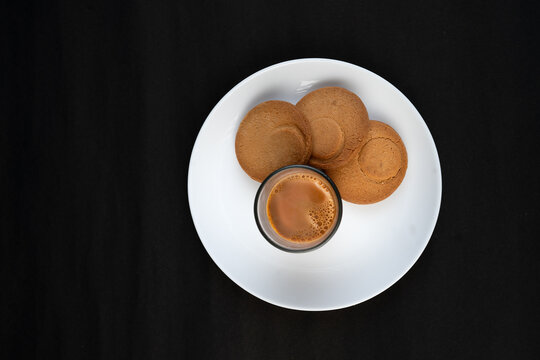 Traditional Indian tea in a clear glass and Biscuit isolated on a black background
