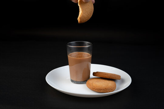 Traditional Indian tea in a clear glass and Biscuit isolated on a black background