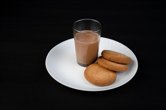 Traditional Indian tea in a clear glass and Biscuit isolated on a black background