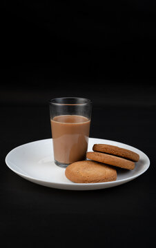 Traditional Indian tea in a clear glass and Biscuit isolated on a black background