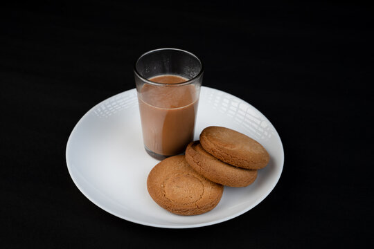 Traditional Indian tea in a clear glass and Biscuit isolated on a black background