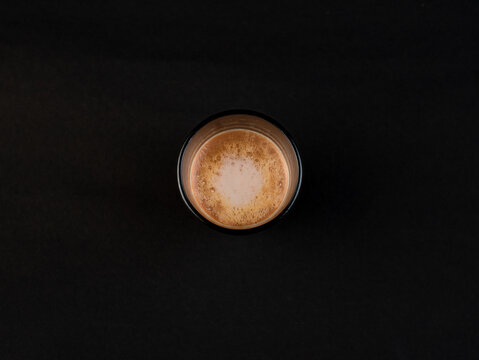 Traditional Indian frothy tea in a clear glass isolated on a black background