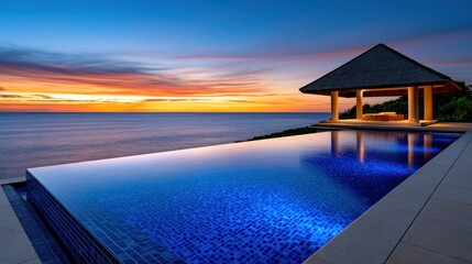 Fototapeta premium Luxury infinity pool overlooking ocean at sunset with gazebo