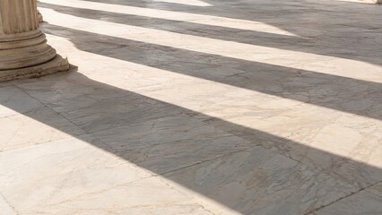 Obraz premium Classical stone columns cast long diagonal shadows across veined marble floor in Greece
