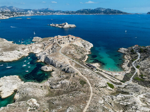 Aerial view of the historic Hopital Caroline on the rocky Frioul islands surrounded by turquoise Mediterranean waters and sailboats in Marseille, Provence-Alpes-Cote d'Azur, France.