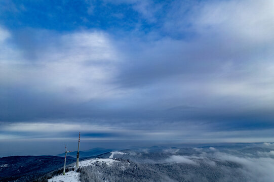 Aerial view of wind turbines on a snow-covered mountain ridge in the Black Forest under a cloudy sky in Seebach, Baden-Wurttemberg, Germany.