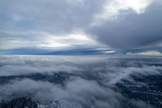 Aerial view of the snow-covered Black Forest landscape near Seebach, with dense mist and low-hanging clouds over the evergreen trees in Seebach, Baden-Wurttemberg, Germany.