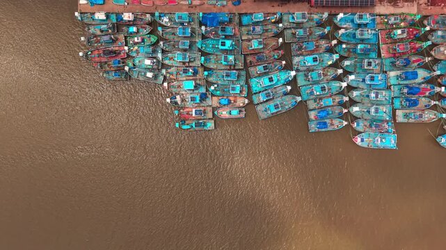 Colourful fishing boats packed tightly together at a busy fishing harbour