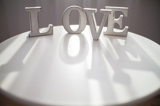 White wooden letters spelling the word love stand on a white round table