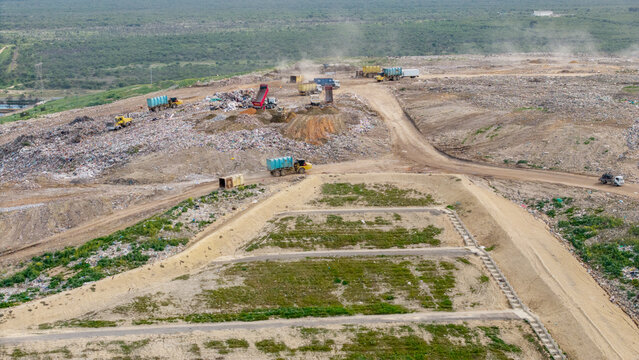 Aerial view of Vissershok Road landfill site with heavy machinery and dump trucks operating on piles of waste in Cape Town, Western Cape, South Africa.