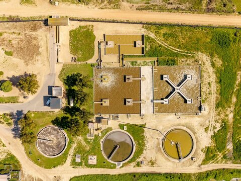 Aerial view of the wastewater treatment plant featuring circular sedimentation tanks and rectangular aeration basins surrounded by rural landscape in Vredenburg, Western Cape, South Africa.