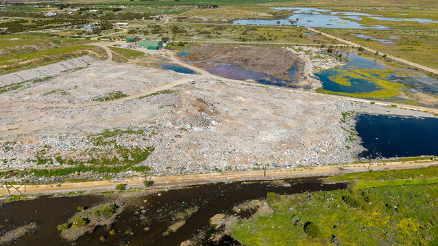 Aerial view of a large landfill site with waste piles and surrounding wetlands in Vredenburg, Western Cape, South Africa.