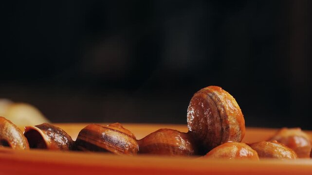 French snails, Close up of traditional spanish tapas - the boiled snails in tomato sauce with garlic and chili in black iron pan