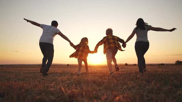 Family running in a field at sunset. Family, silhouette, running, park running together, sunset. Family running together at sunset. Lifestyle.