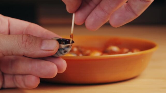 French snails, Close up of traditional spanish tapas - the boiled snails in tomato sauce with garlic and chili in black iron pan