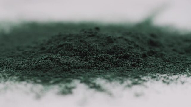 Green chlorella algae powder on a wooden spoon, top view. Healthy nutritional supplement.