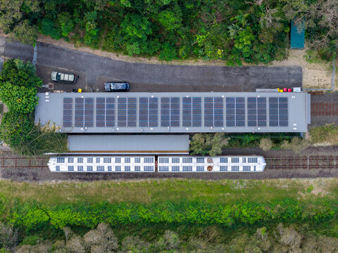 Aerial view of the world's first solar power train with solar panels on its roof parked next to a station building with solar panels in Byron Bay, New South Wales, Australia.