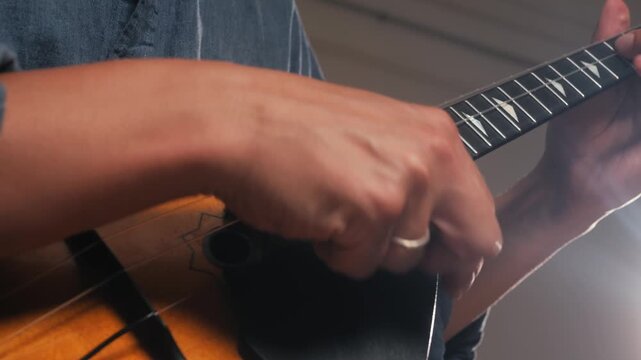 Man playing on slavic string guitar balalaika at home, closeup view on hands and strings, musician on concert. 