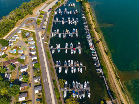 Aerial view of the marina in Vogelgrun with rows of docked boats, calm water, surrounding green landscape, and nearby residential houses in Vogelgrun, Grand Est, France.